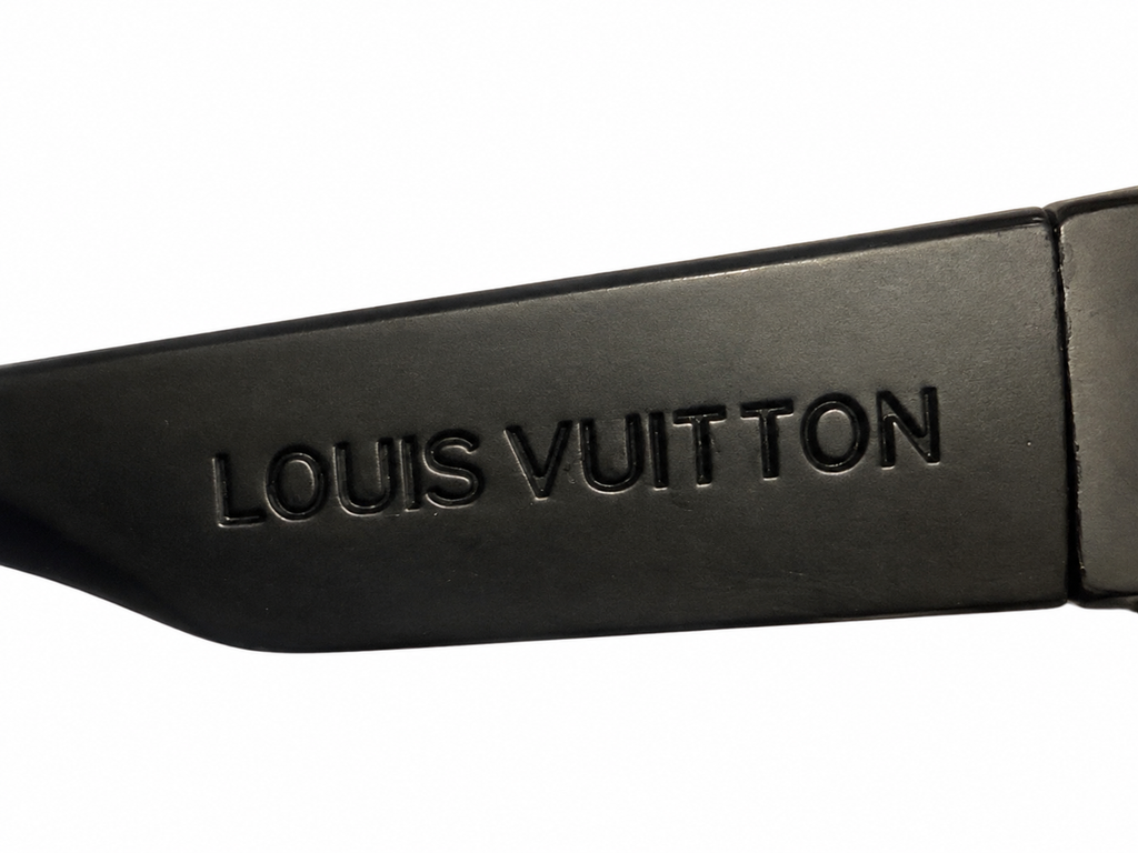 Close-up of the embossed Louis Vuitton wordmark on the sunglasses temple against white.